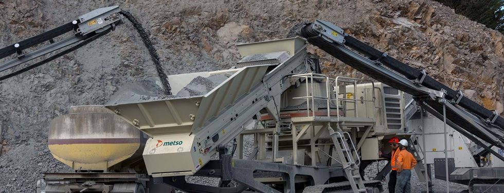 Two men next to mobile crusher with Barmac VSI crusher.