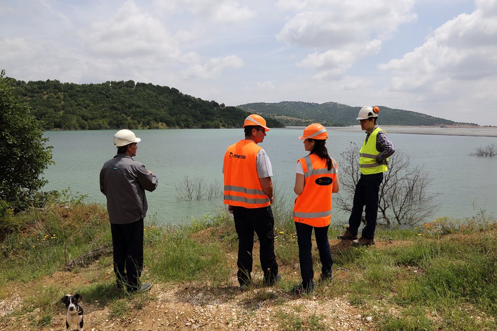 Four people standing by water near Bucim mine.